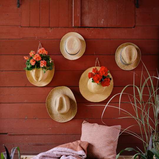 Wandschmuck im Boho-Stil: blühende Sommerstrohhüte